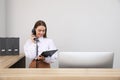 Female receptionist with clipboard talking on phone at workplace. Space for text Royalty Free Stock Photo