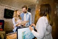 Female receptionist giving tourist information to happy young couple, holding the city map, standing at the hotel Royalty Free Stock Photo