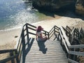 female in a red hat on the wooden steps of the stairs on the beach in Portugal Royalty Free Stock Photo