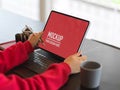 Female in red sweater hands using mock up tablet on table Royalty Free Stock Photo