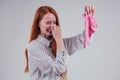 Female redhead in a striped shirt gesture smells bad holding a dirty pink sock out a disgusted look on her face in Royalty Free Stock Photo