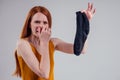 Female redhead in a in a yellow shirt gesture smells bad holding a dirty black male sock out a disgusted look on her Royalty Free Stock Photo