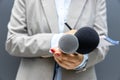 Female journalist at news conference or media event, writing notes, holding microphone Royalty Free Stock Photo