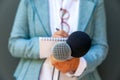 Female journalist at news conference or media event, writing notes, holding microphone Royalty Free Stock Photo