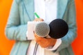 Female journalist at news conference or media event, writing notes, holding microphone Royalty Free Stock Photo