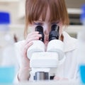 Female researcher using a microscope in a lab