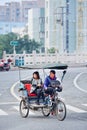 Female rickshaw driver with a passenger waiting on a juntion, Wenzhou, China