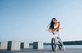 Female rider is on the bike at daytime near the lake. Fitness woman in sportive clothes