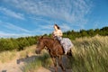 Female riding a horse in a green field on a blustery day