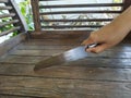 Female right hand with Steel kitchen knife on brown wooden chair