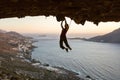 Female rock climber on challenging route in cave at sunset