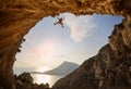 Female rock climber hanging on rope while lead climbing in cave with beautiful sea view Royalty Free Stock Photo