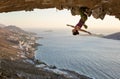 Female rock climber hanging upside down on challenging route in cave at sunset Royalty Free Stock Photo