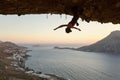 Female rock climber hanging upside down on challenging route in cave at sunset Royalty Free Stock Photo