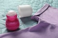Female roll-on deodorant and lilac t-shirt on bed