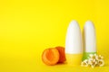 Female roll-on deodorants, apricots and chamomile flowers on yellow background