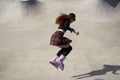 Female roller blader jumping in a skate pool outdoor. Young adult skater in aggressive inline skates riding in a concrete bowl in