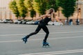 Female roller demonstrates her abilities of rollerblading rides very quckly on road along city enjoys sunny day