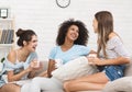 Female roommates gossiping and laughing, drinking coffee