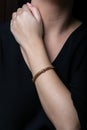 Female, rose gold wicker bracelet with insert in the middle, on hand, on a black background. Royalty Free Stock Photo