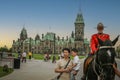 Female Royal Canadian mounted police officer on horseback with visitors in front of Parliament Hill