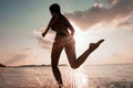 Female Runner on the Beach at Sunset silhouette in air farther Royalty Free Stock Photo