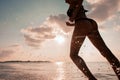 Female Runner on the Beach at Sunset silhouette in air farther Royalty Free Stock Photo