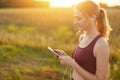 Female runner enjoying calm atmosphere while jogging on field, listening to her favourite track in earphones. Young female going i