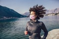 Female runner jogging with protective mask during outdoor workout on beach Royalty Free Stock Photo