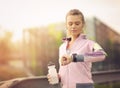 Woman running at sunset in city park using smart watch and earbuds Royalty Free Stock Photo