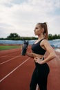 Female runner drinks water, training on stadium