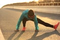 Female runner stretching her legs on sunrise road