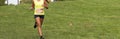 Female running downhill on grass field during 5K cross country race with plenty of copy space