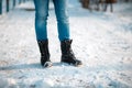Female`s feet in close-up, wearing boots with anti-slip protectors. Snow in the background. Copy space