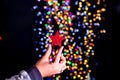 Female's hand holding a Christmas glittery star decoration near a wall with blurred lights