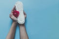 Female`s hand holding sanitary napkins with red rose on it. Period days concept showing feminine menstrual cycle. Female`s hygie