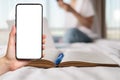 A female`s hand holds a smartphone with a white screen. Mock up. In the background is an open book and the silhouette of a woman. Royalty Free Stock Photo