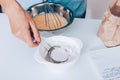 Female`s hand scoop flour in sieve to sift it into dough