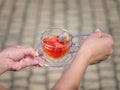A female`s hands with a cup of berries liquid on a stone blurred background. Delicious and natural strawberry tea. Royalty Free Stock Photo