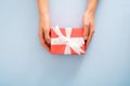 Female`s hands holding red gift box with white ribbon bow on pastel blue background. Christmas, New Year, Valentine`s day and Royalty Free Stock Photo