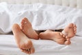 Female`s and male`s bare feet have rest under white blanket, rec