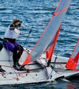 Female sailing a racing dinghy with a milar sail on an inland waterway