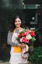 Female sales assistant working as florist and holding bouquet