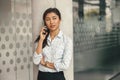 Female sales manager talking phone with client while standing in coworking and looking at side Royalty Free Stock Photo