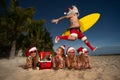 Female Santas relaxing on the beach with Santa Claus, drinking champagne and fruits Royalty Free Stock Photo