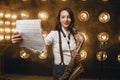 Female saxophonist with saxophone holds music book
