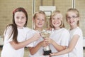 Female School Sports Team In Gym With Trophy