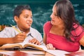 Female School Teacher Doing Homework with a Young Hispanic Boy in the Classroom Royalty Free Stock Photo