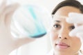 Female Scientist Analyzing Solution In Petri Dish At Laboratory