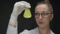 Female Scientist Checking in Test flask Chemical Liquid with dark precipitate